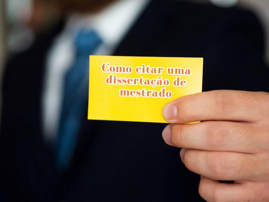 Mão segurando um cartão com dicas sobre como citar uma dissertação de mestrado corretamente.