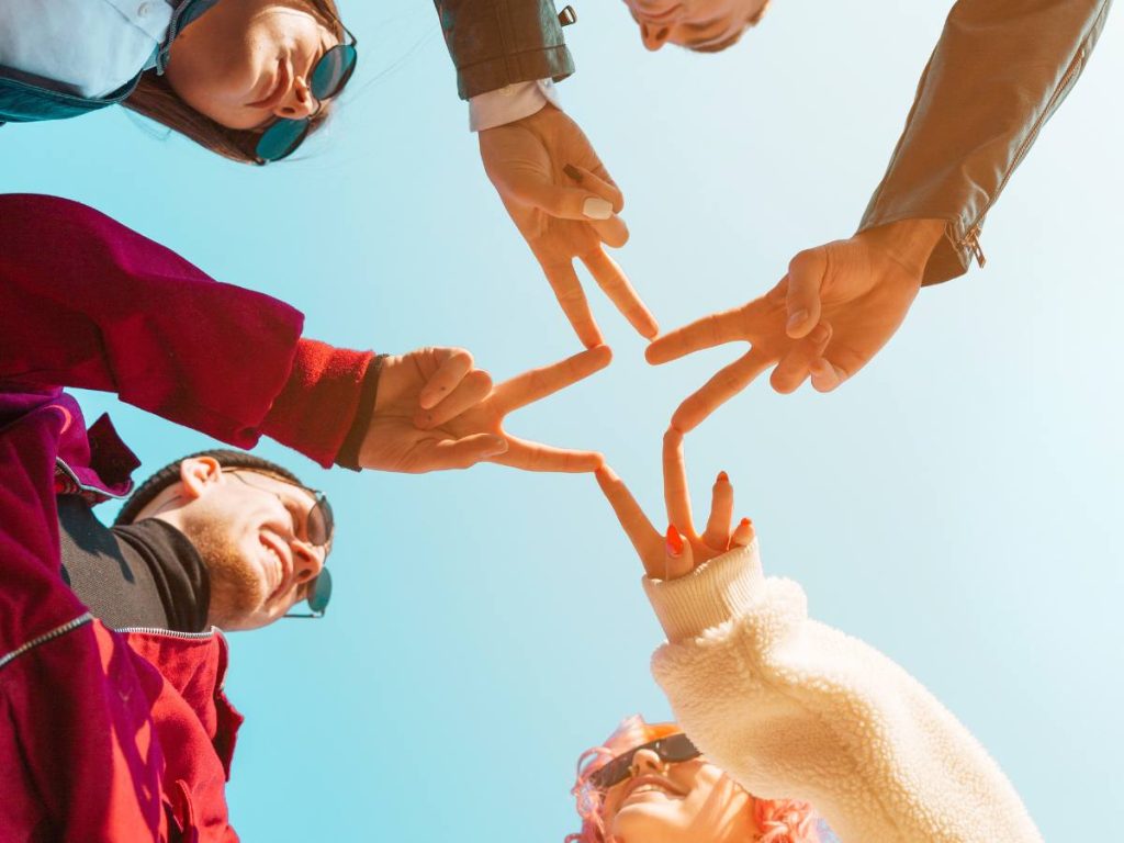Grupo de pessoas unindo as mãos em solidariedade, representando a colaboração em projetos de mestrado em serviço social.