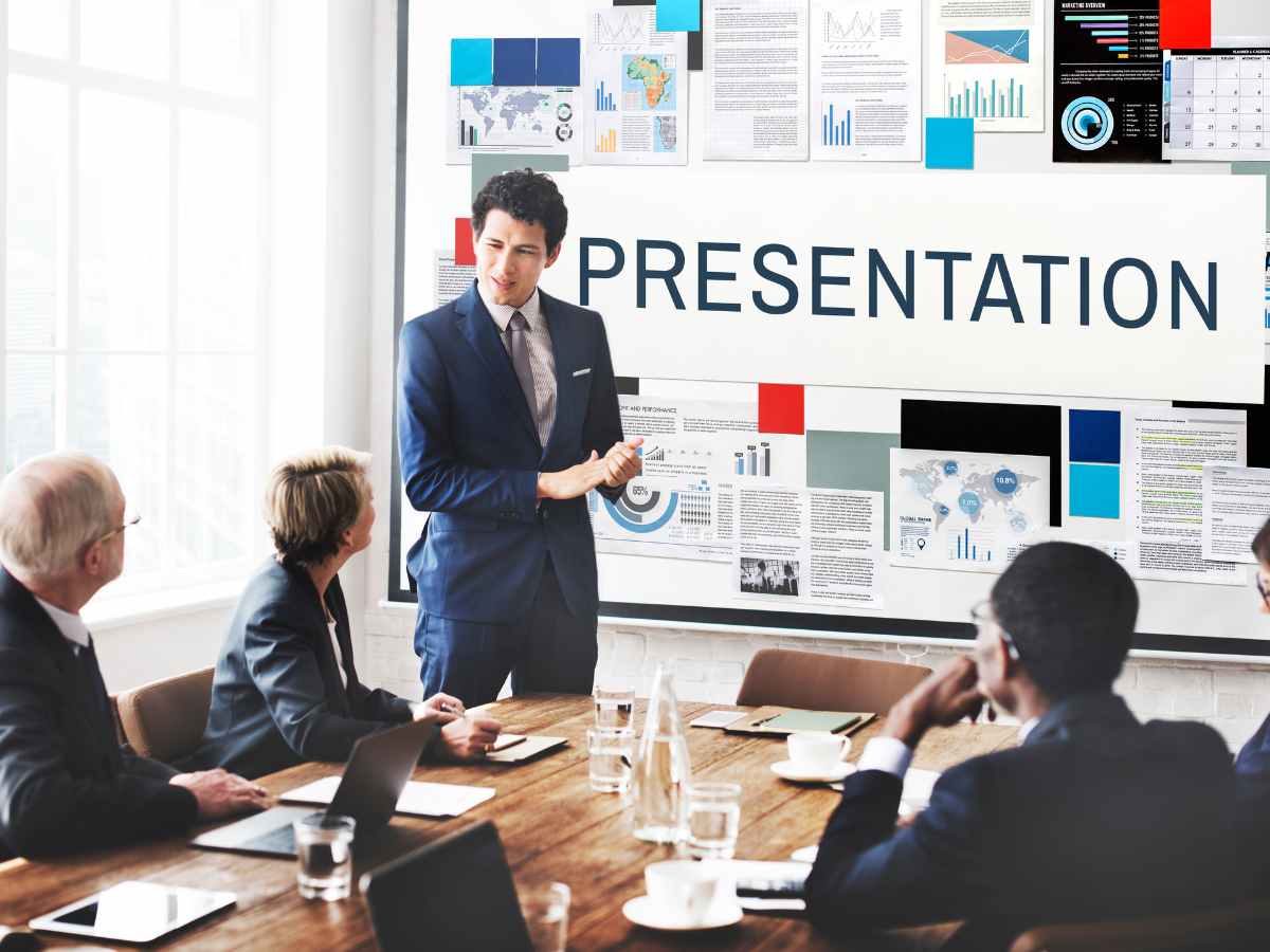 Homem fazendo apresentação de gráficos e dados em uma sala de conferências.