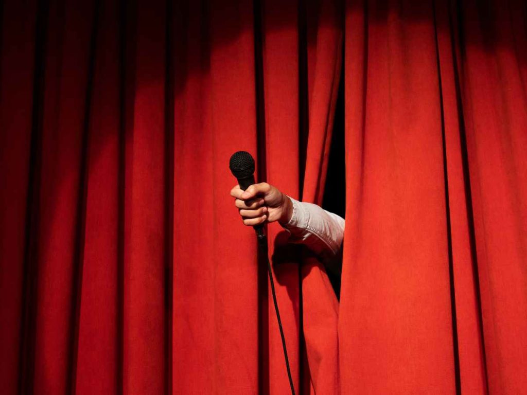 Preparação para uma apresentação de teatro com microfone na mão, representando a iniciação no palco
